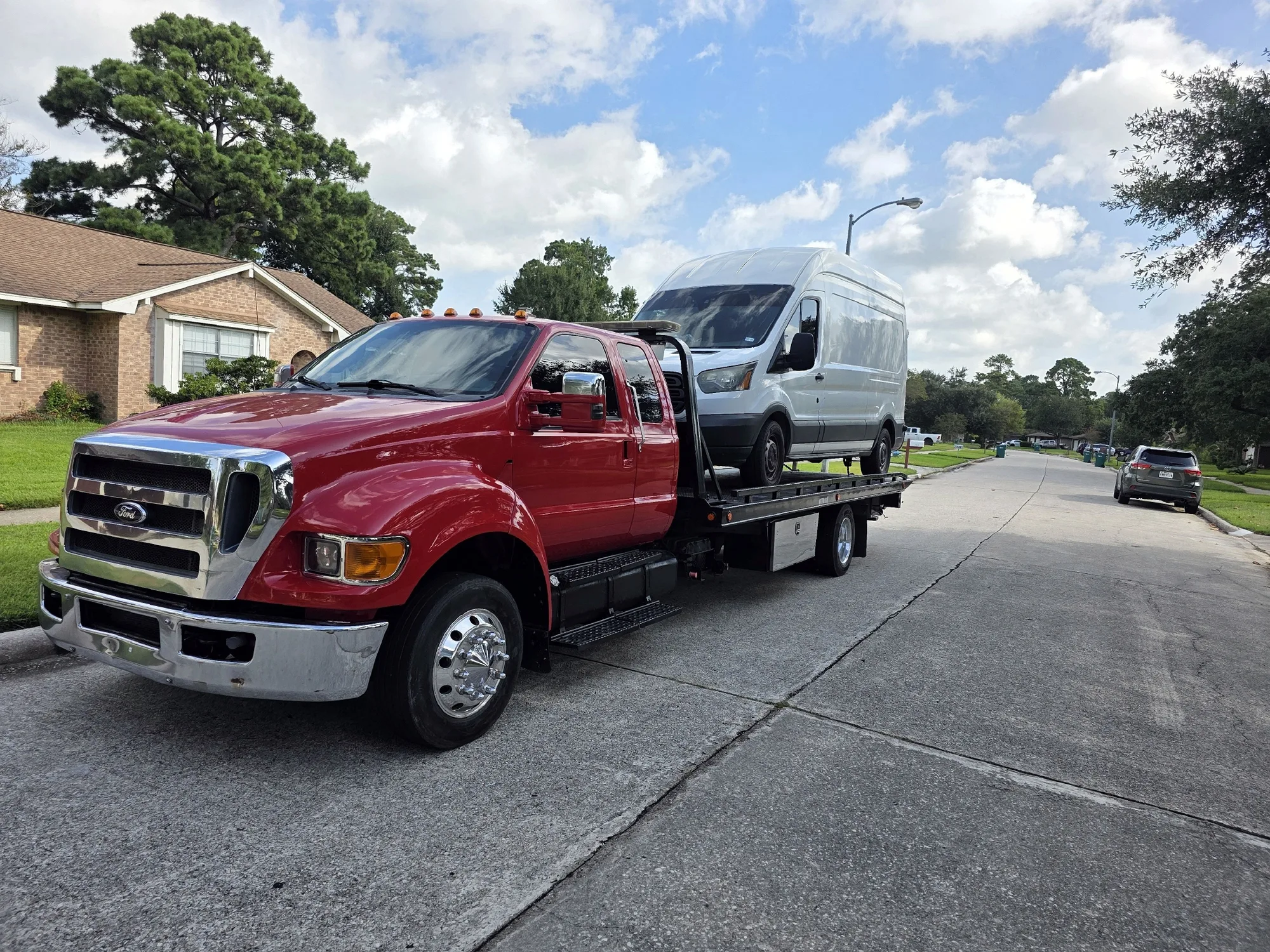 DMC flatbed removing a white van from a residential street