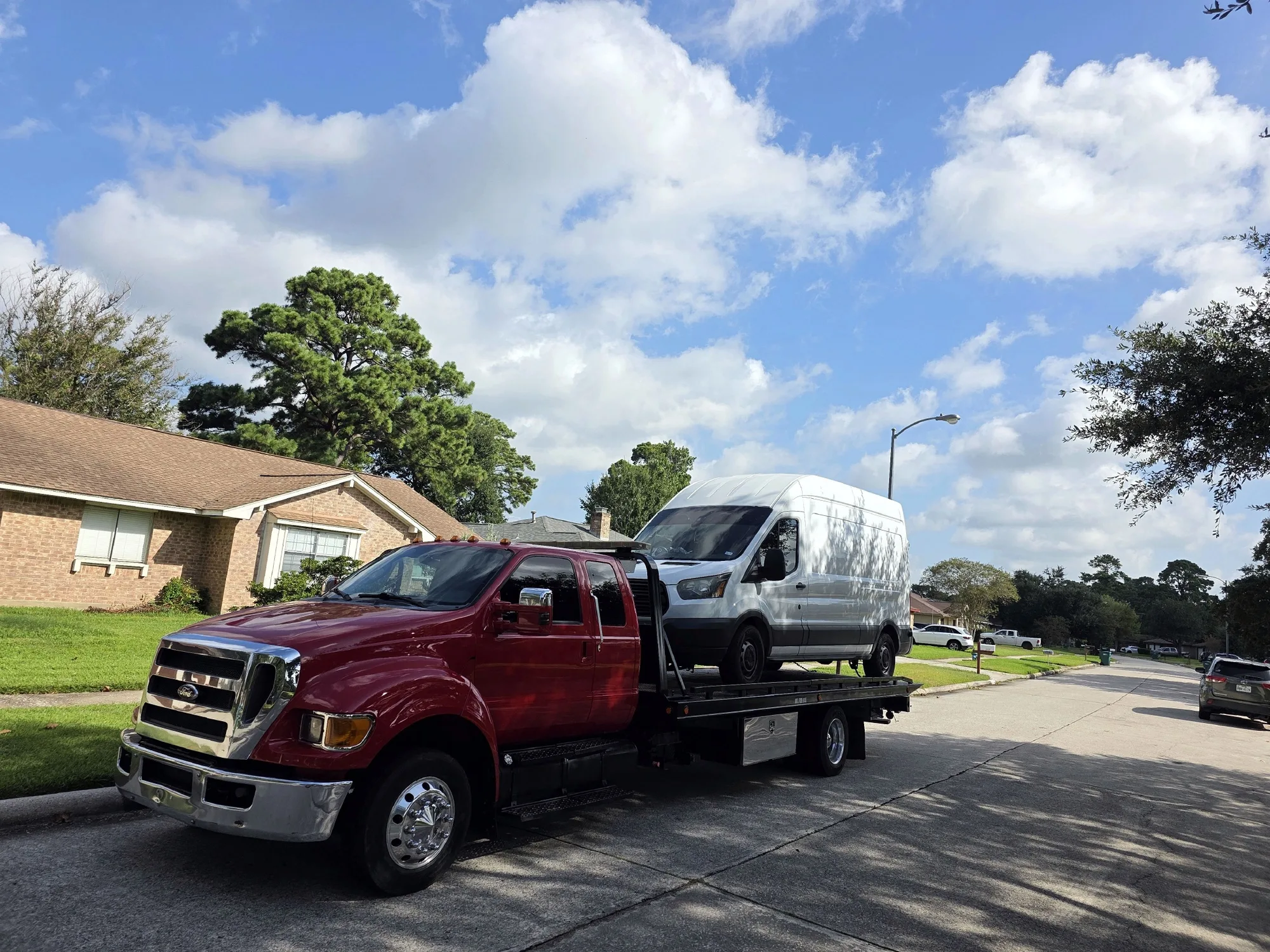 DMC tow truck loading a white cargo van in a Spring, TX neighborhood